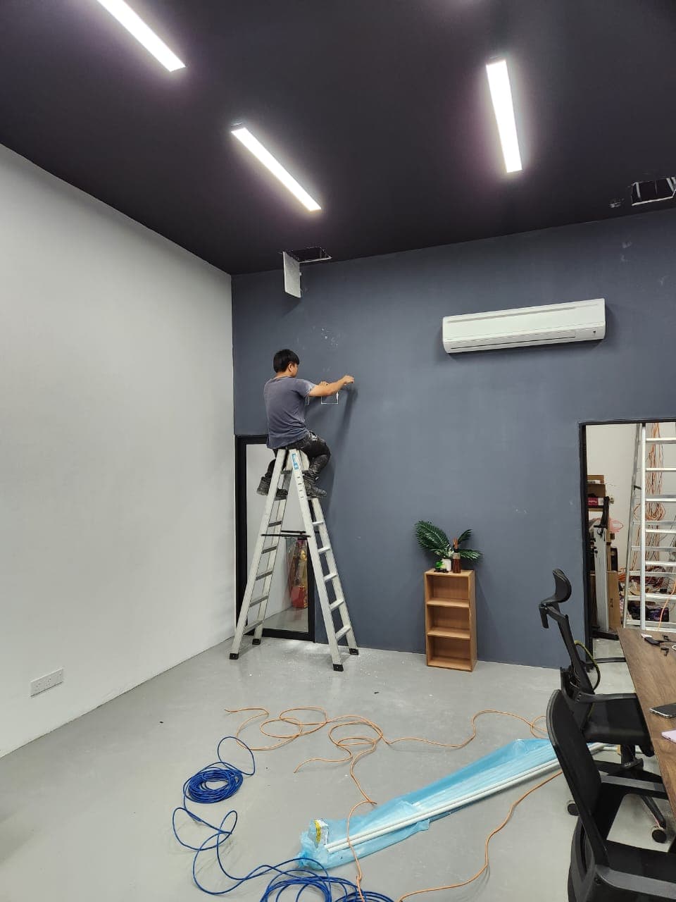 Installer on a ladder preparing wall cabling for keyphone and intercom installation
